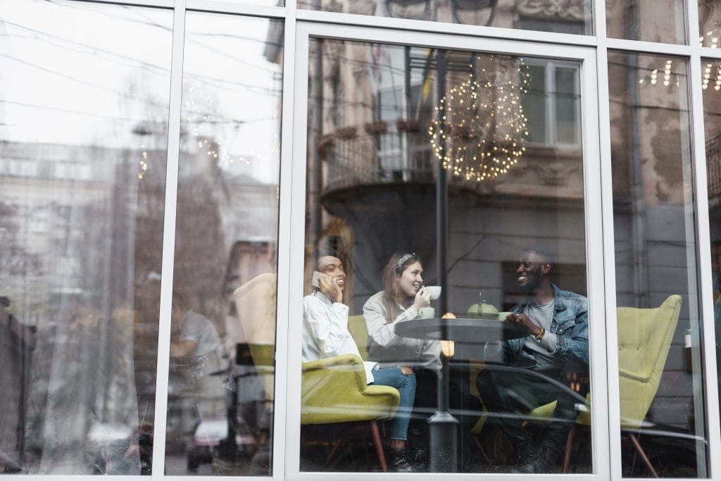Gasten drinken koffie achter de heldere ruiten van een horecazaak