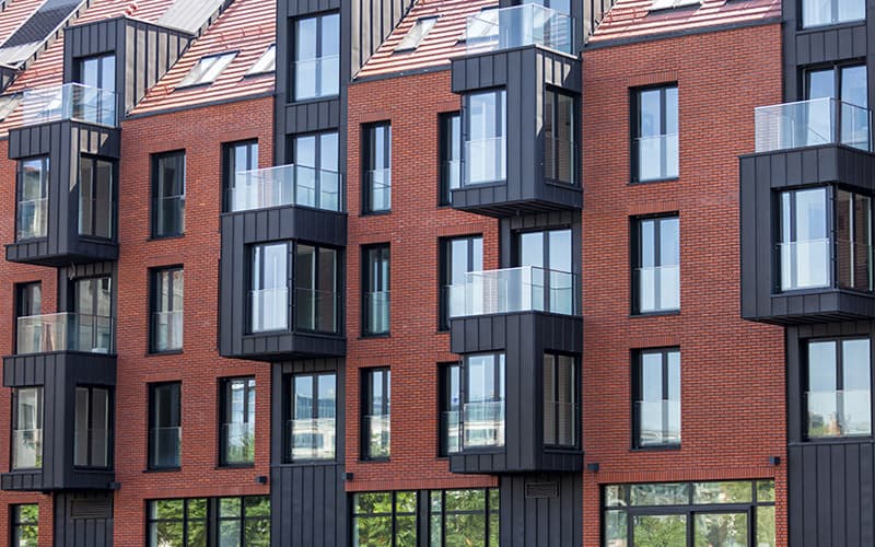 Modern appartementencomplex met rode baksteen, zwarte kozijnen en glazen balkons